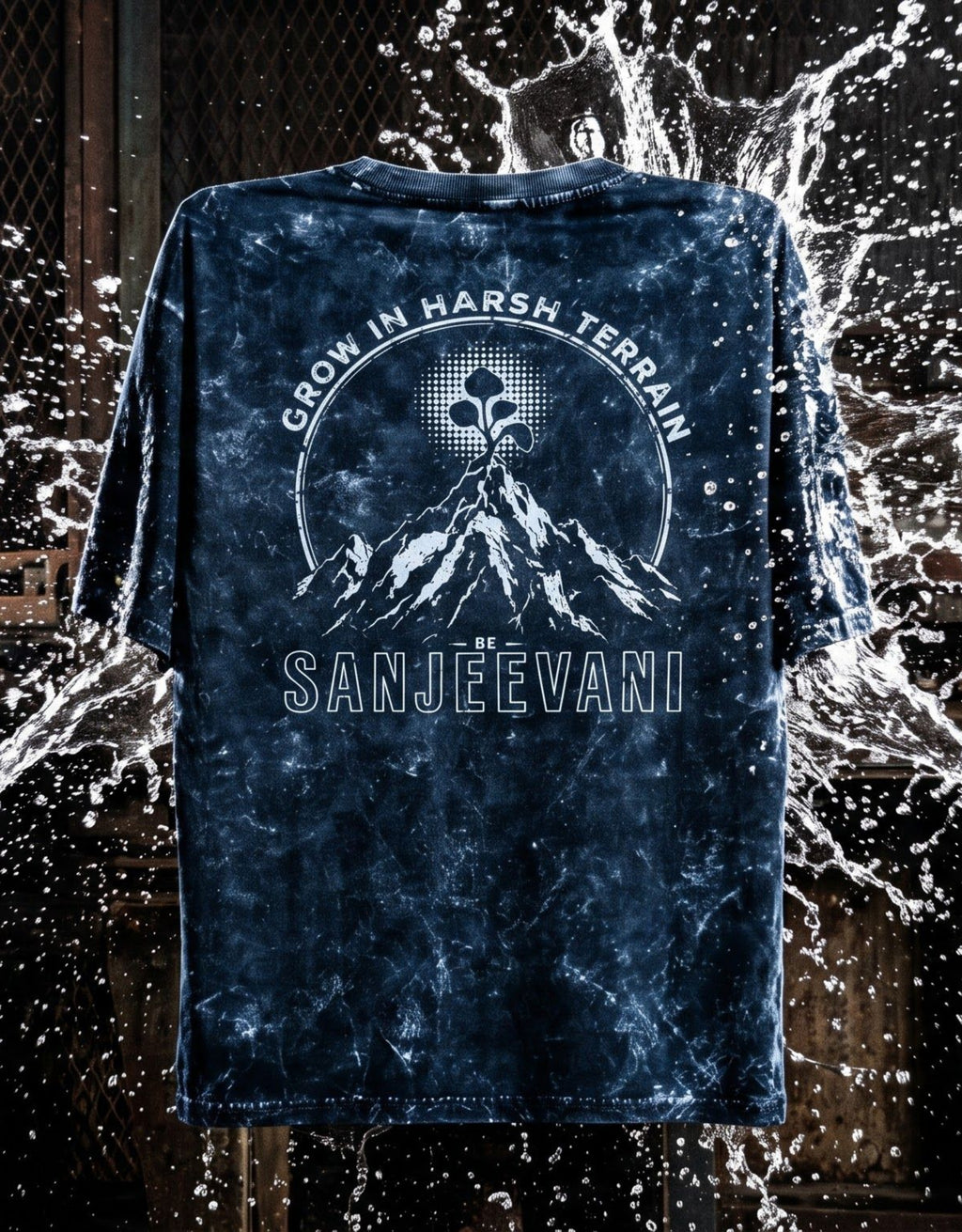 A dark navy blue short-sleeve acid wash t-shirt, featuring a mountain and a ethereal flower with the text 'GROW IN HARSH TERRAIN' and 'SANJEEVANI'. The shirt is displayed against a dark background with a water splash effect.