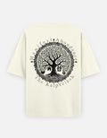 An off-white short-sleeve t-shirt with a large black circular graphic on the back, featuring a tree of wish - The KalpVriksh, and the text 'Manifest Abundance | The KalpVriksh'.